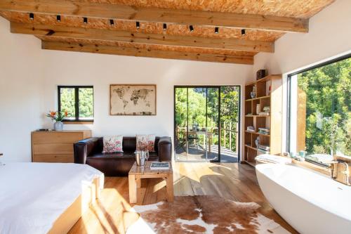 a room with a bed and a tub and a couch at Granite Forest Chalet in Cape Town