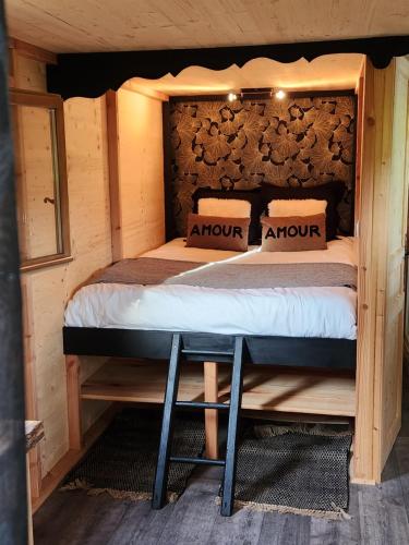 a bed in a cabin with a wooden headboard at le cocon d'amour " Roulotte avec jaccuzi privé " in La Chapelle-du-Fest