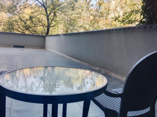 a glass table and two chairs on a patio at Sava apartment in Novi Sad