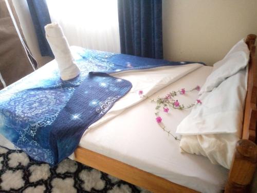 ein Bett mit einer blauen Decke und Blumen darauf in der Unterkunft Pelia Rose Guesthouse in Kisumu