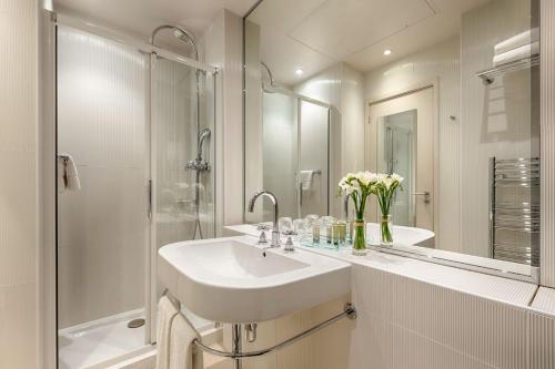 a white bathroom with a sink and a shower at Floride-Etoile in Paris