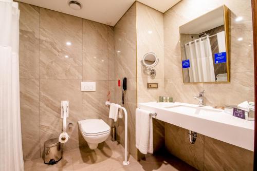 a bathroom with a sink and a toilet and a mirror at Doubletree By Hilton Antalya City Centre in Antalya