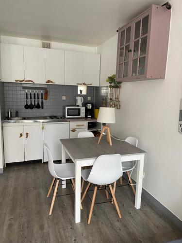 une cuisine avec des armoires blanches et une table et des chaises dans l'établissement Plage et commerces à 50m, sans télé pour déconnecter !, à Houlgate
