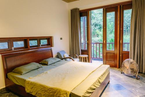 ein Schlafzimmer mit einem großen Bett und einem Balkon in der Unterkunft Leela Village - Playground For Buddhas in Hanoi