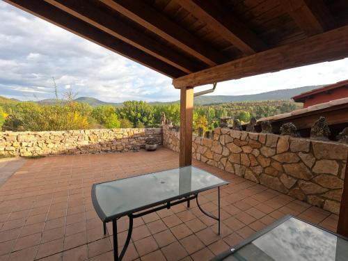 einen Glastisch auf einer Terrasse mit einer Steinmauer in der Unterkunft Casa el Escalerón in Uña