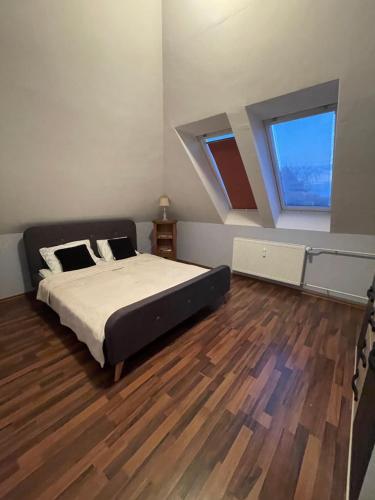 a bedroom with a bed and a wooden floor at Palank Apartman in Mosonmagyaróvár