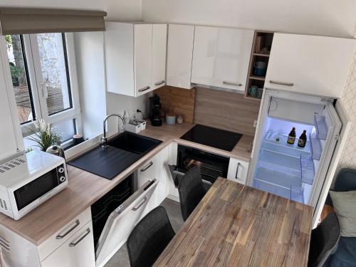 a small kitchen with white cabinets and a wooden table at L’Aragne in Dinant