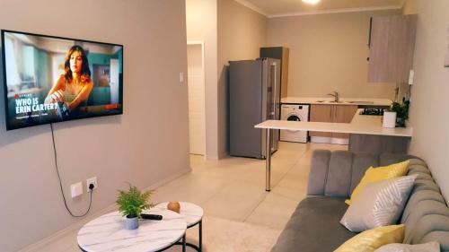 a living room with a couch and a tv on a wall at Midrand Serene Escape in Midrand