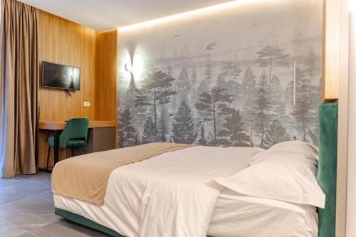 a bedroom with a bed with a painting on the wall at Hotel INA in Borşa
