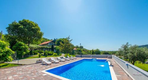 a large swimming pool with lounge chairs and a resort at Villa Ellie in Ljubuški