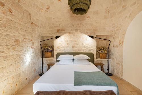 a bedroom with a bed in a stone wall at Trullo Due Ulivi in Monopoli
