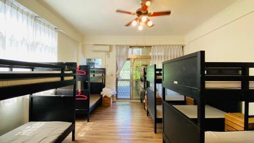 a room with several bunk beds and a ceiling fan at Luye Jamie's Guesthouse in Luye