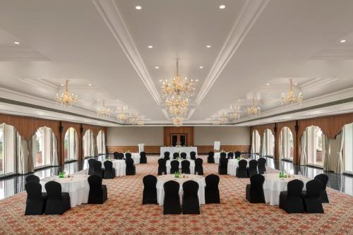 a ballroom with tables and chairs and chandeliers at Uday Palace Navsari, a member of Radisson Individuals in Navsāri