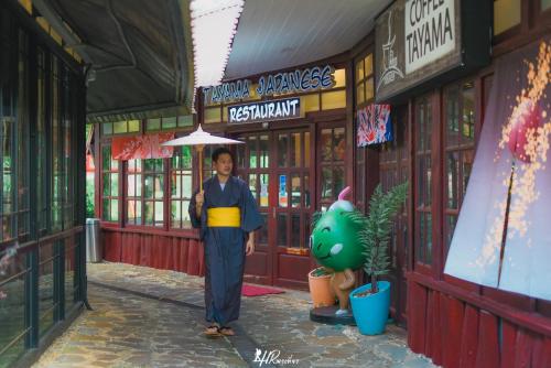 a man standing in front of a building with an umbrella at Tayama Farm Khaoyai in Nakhon Ratchasima
