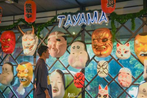 a man standing in front of a wall with masks at Tayama Farm Khaoyai in Nakhon Ratchasima