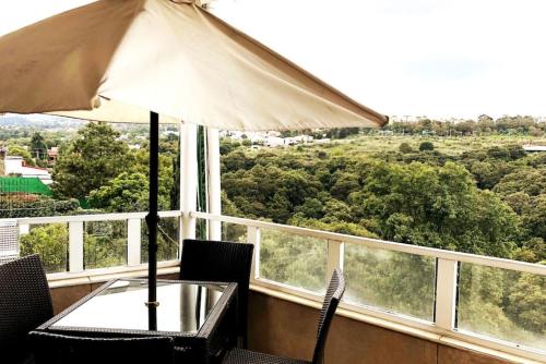 a table and chairs with an umbrella on a balcony at Views from the Heart of theForest ,Wi-Fi, TV, Terrace in Mexico City