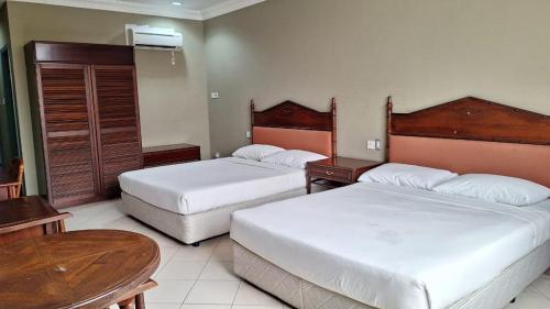 ein Hotelzimmer mit 2 Betten und einem Tisch in der Unterkunft Hotel Ming Kiong 