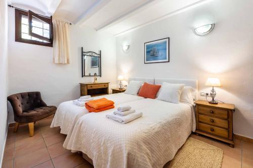 a bedroom with a large white bed with a chair at Villa Marilina in Sant Miquel de Balansat