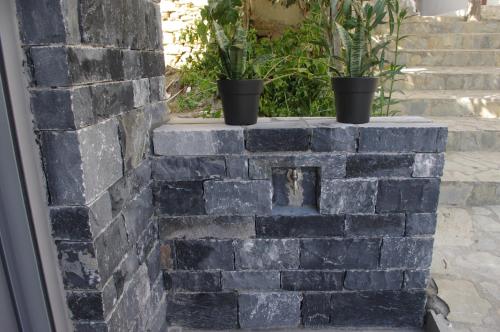 a brick wall with two potted plants on top at Irene Luxury Apartments in Myrtos