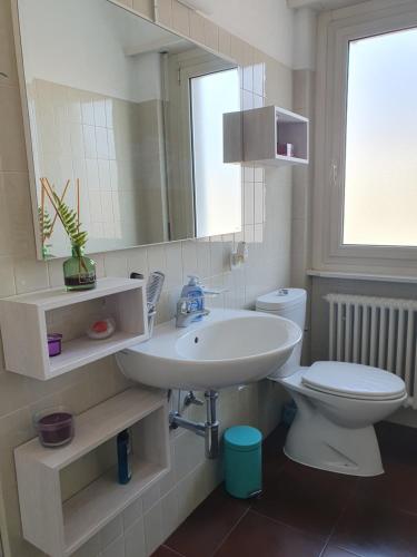 a bathroom with a sink and a toilet and a mirror at Charming Penthouse near Como lake in Chiasso