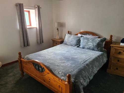 a bedroom with a wooden bed with blue pillows at Brown Cow Apartment in Dalton in Furness