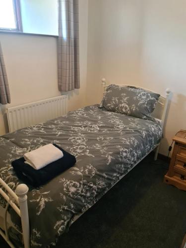 a bedroom with a bed with a black and white comforter at Brown Cow Apartment in Dalton in Furness