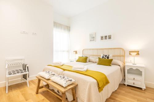 biała sypialnia z dużym łóżkiem i krzesłem w obiekcie Magno Apartments Casa del Correo Mayor II w Sewilli