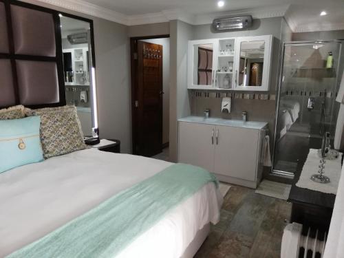 a bedroom with a bed and a bathroom with a sink at 94 Sea Cottage in Mossel Bay