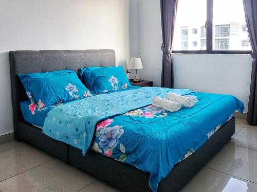 Una cama con sábanas azules y dos toallas. en D Casa Cattleya Desaru en Kota Tinggi