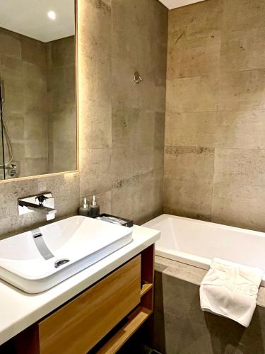 a bathroom with a white sink and a bath tub at Estrella Boutique Hotel in Da Nang