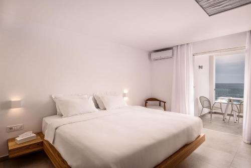 a white bedroom with a large bed and a balcony at Kantouni Beach Boutique Hotel in Panormos Kalymnos