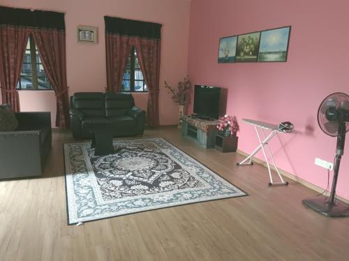 sala de estar con silla verde y alfombra en Homestay Murah Umbai Melaka, en Merlimau