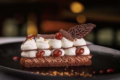 uma sobremesa com marshmallows e bolachas num prato preto em Golf Hotel Resort Du Val De Sorne em Vernantois