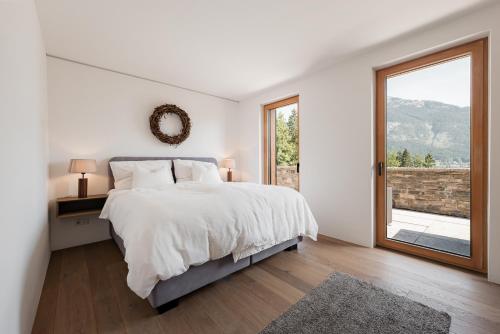 a white bedroom with a large bed and a window at Villa Seeblick in Altaussee