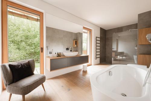 a bathroom with a tub and a chair and a sink at Villa Seeblick in Altaussee