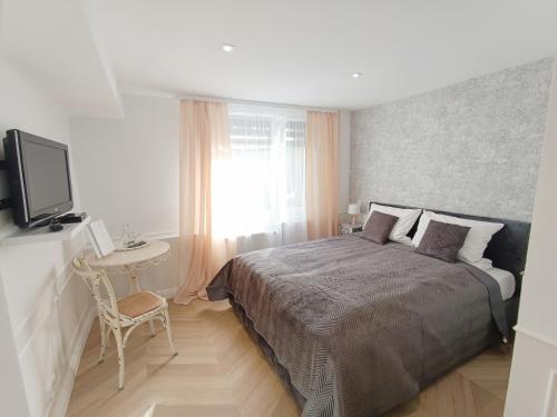 a bedroom with a bed and a table and a television at Złoty Lin in Serock