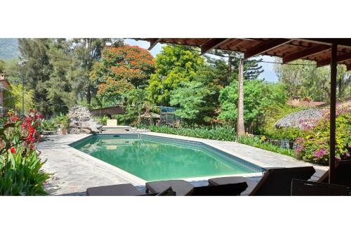 a swimming pool in a yard with chairs and flowers at Capital O Posada Del Pescador in Chapala