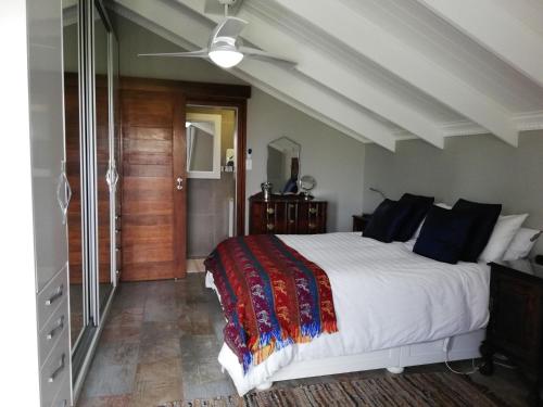 a bedroom with a bed and a ceiling fan at 94 Sea Cottage in Mossel Bay