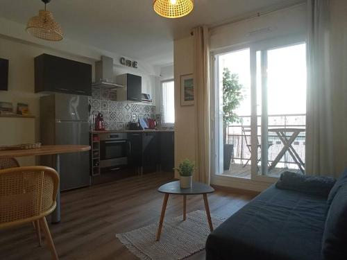 ein Wohnzimmer mit einem Sofa und einem Tisch sowie eine Küche in der Unterkunft A 50 m de la plage, appartement de 35 m2 : Les pieds salés in Bréhal