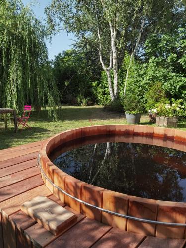 a wooden deck with a pond in the middle of a yard at 2 chambres avec jardin et jacuzzi dans une maison familiale in Noisy-le-Roi