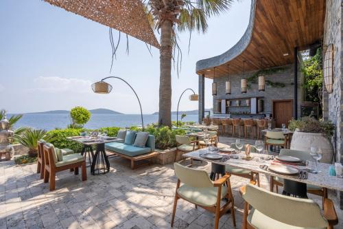 an outdoor patio with tables and chairs and the ocean at Del Mare Reserve Hotel & Spa Bodrum in Bodrum City