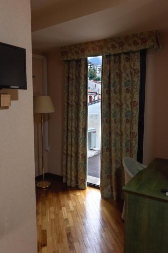 a room with a large window with curtains and a wooden floor at Hotel San Nicola in Lagonegro