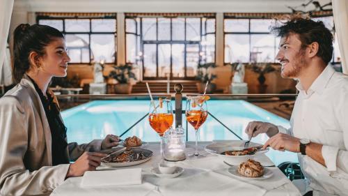 a man and woman sitting at a table eating food at Boutique Hotel Sunstar Brissago am Lago Maggiore in Brissago