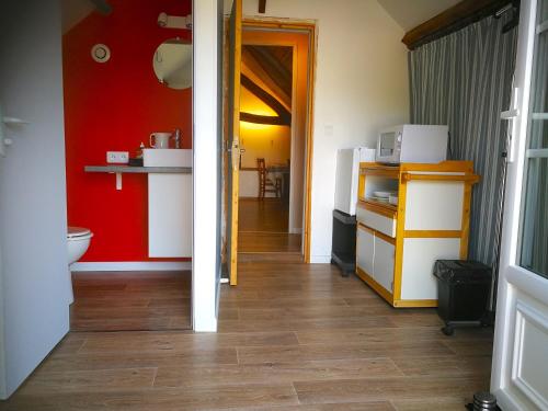 a bathroom with a red wall and a toilet at La Longère aux Volets Rouges, Meublé Tourisme 2 étoiles in Maillebois