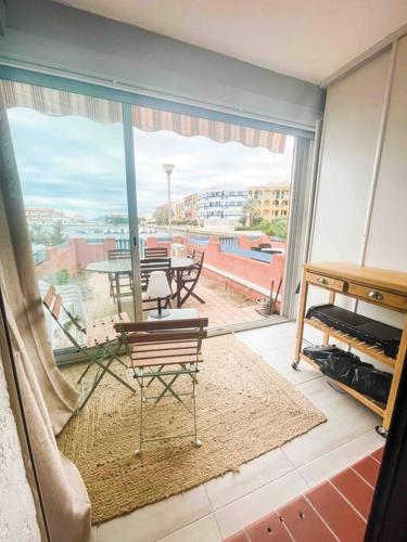 Cette chambre dispose d'une grande fenêtre, d'une table et de chaises. dans l'établissement La Casita ,Appartement face à l’étang, au Barcarès