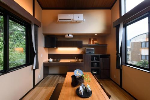 a small kitchen with a wooden table and windows at スタジオーネ箱根彫刻の森 in Hakone