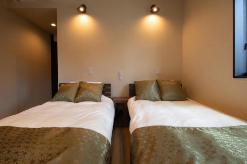 スタジオーネ箱根彫刻の森 في هاكوني: سريرين في غرفة مع أضواء على الحائط