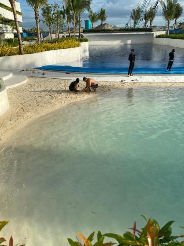 a group of people standing on the beach near a swimming pool at Crissome Suite Azure North San Fernando Pampanga in Lagundi