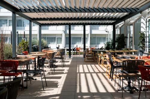 an empty patio with tables and chairs in a building at Novotel Chartres in Chartres