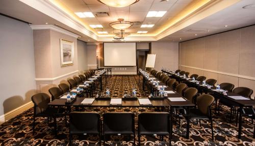 a conference room with long tables and chairs and a screen at Southern Sun Maputo in Maputo